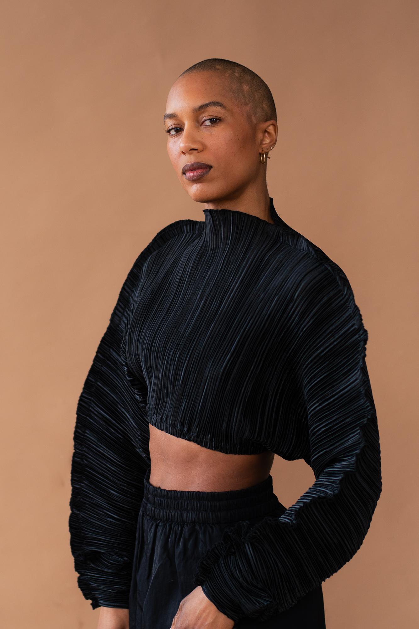 Catherine Kirk in an all black outfit against a light brown backdrop